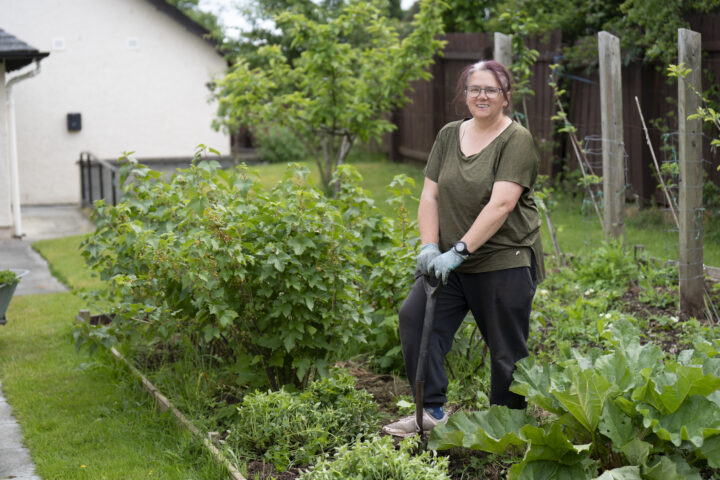 A woman gardening in a garden with a spade.