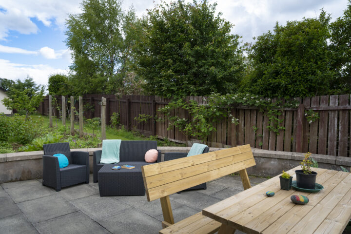 Garden image with a picnic table and benches and garden furniture.