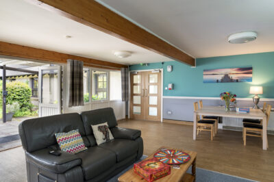 A lounge with sofa, coffee table and dining table and chairs in the background.