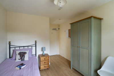 A single bedroom with bed, side table and wardrobe.