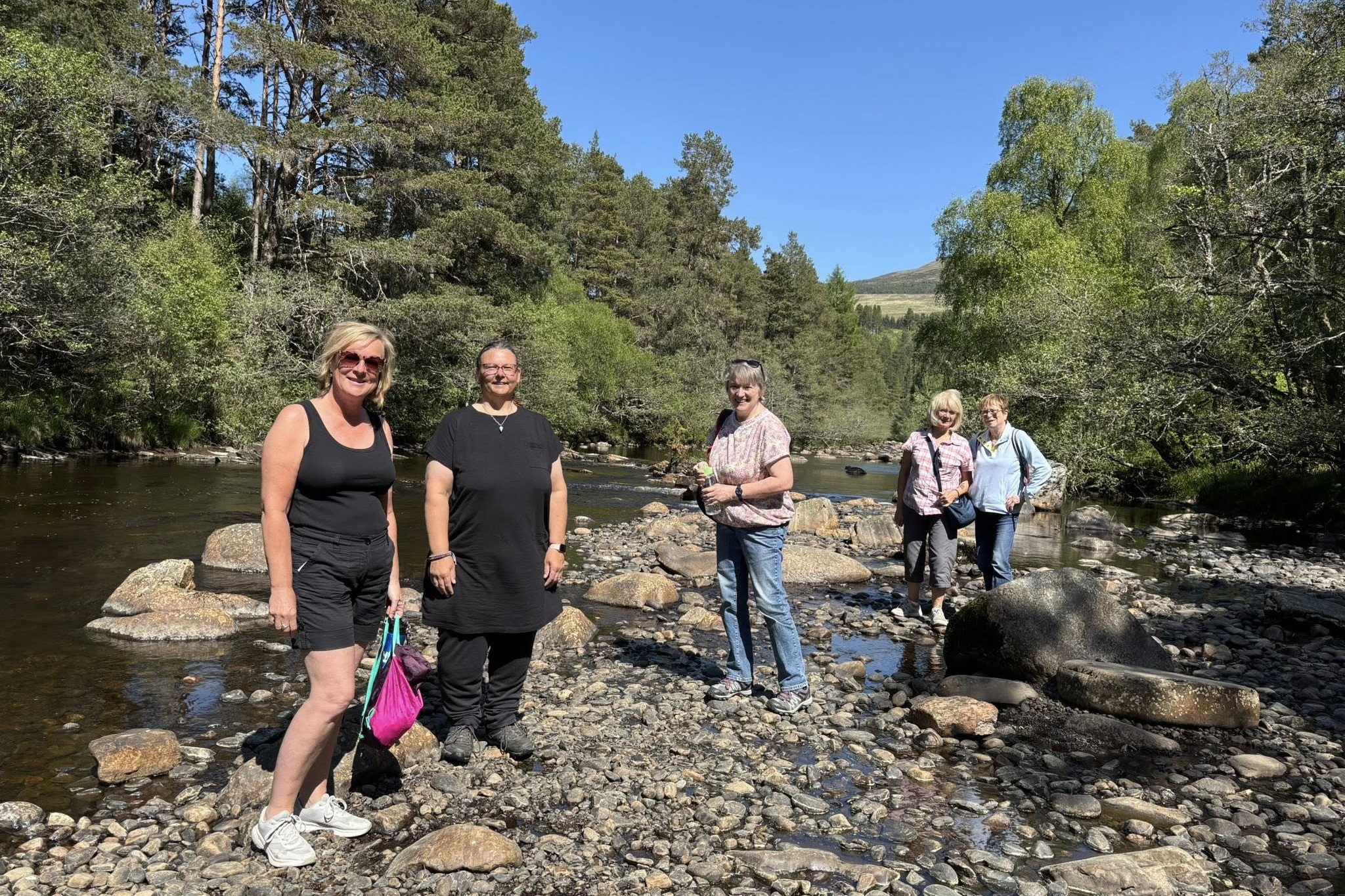 Group of people walking together next to a river.