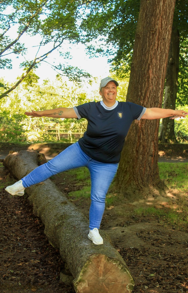 Woman balancing on a tree trunk smiling