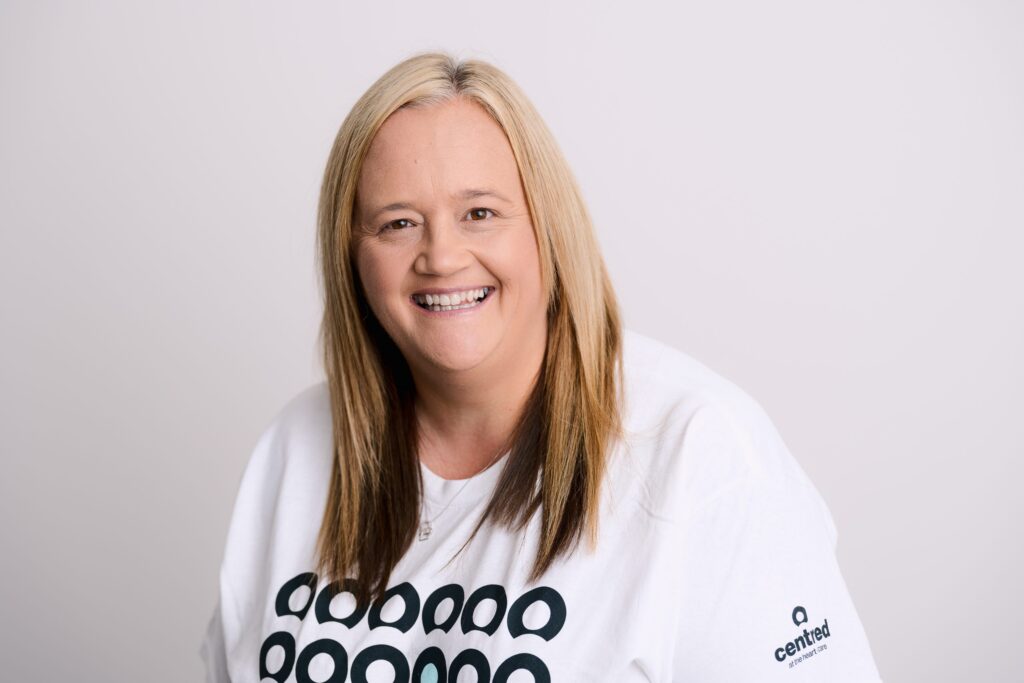 Woman with long blonde hair and t-shirt smiling.