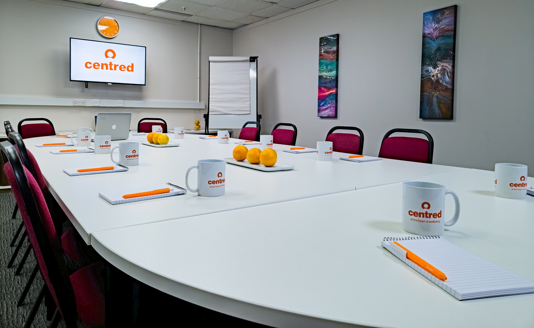 Boardroom with large white table, screen and flipchart.