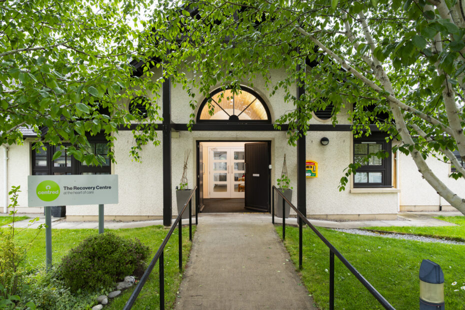 Outside of a Recovery Centre building with trees and grass.