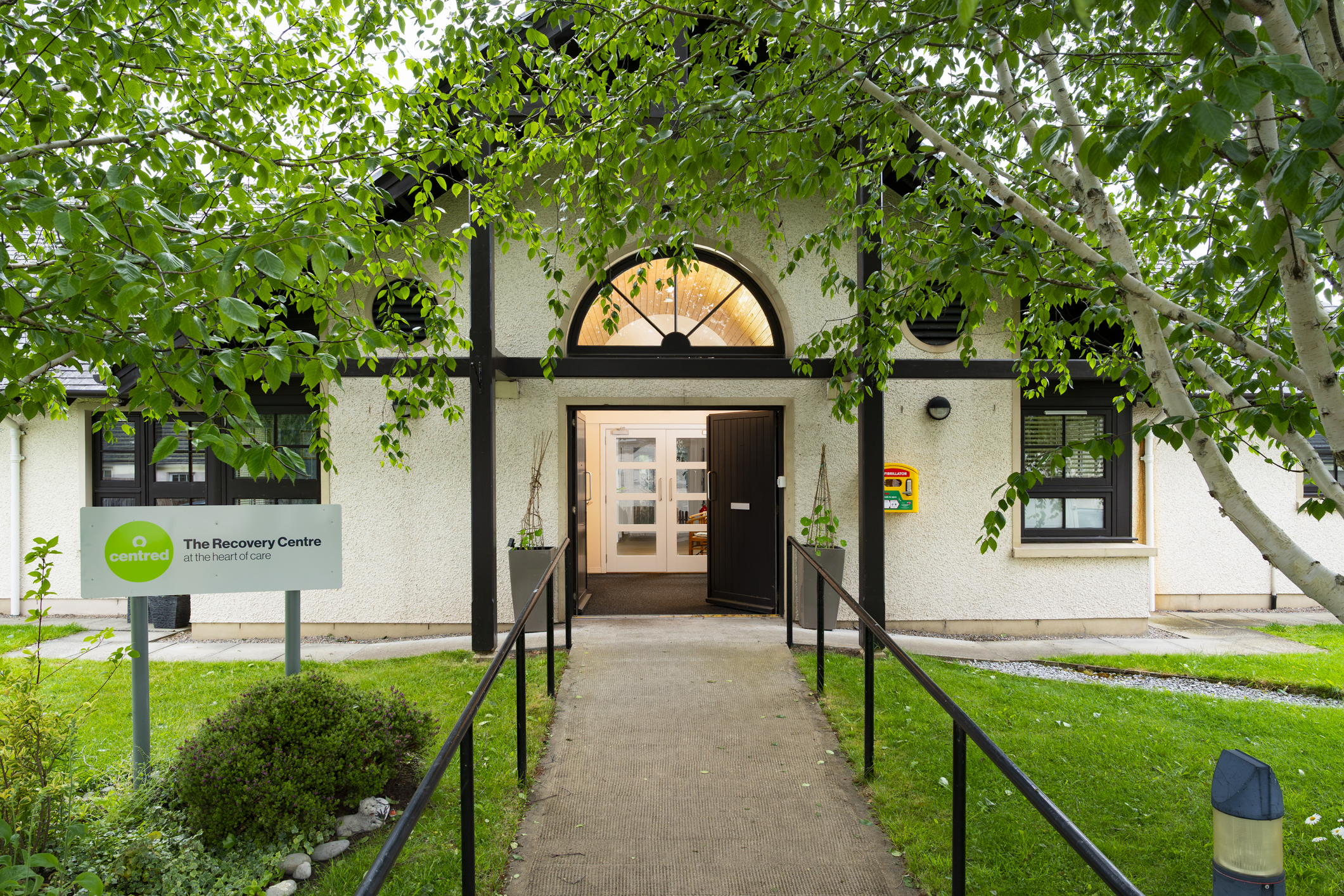 Outside of a Recovery Centre building with trees and grass.