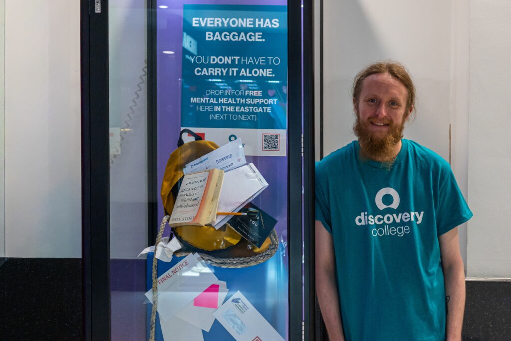 Man standing next to display cabinet about mental health