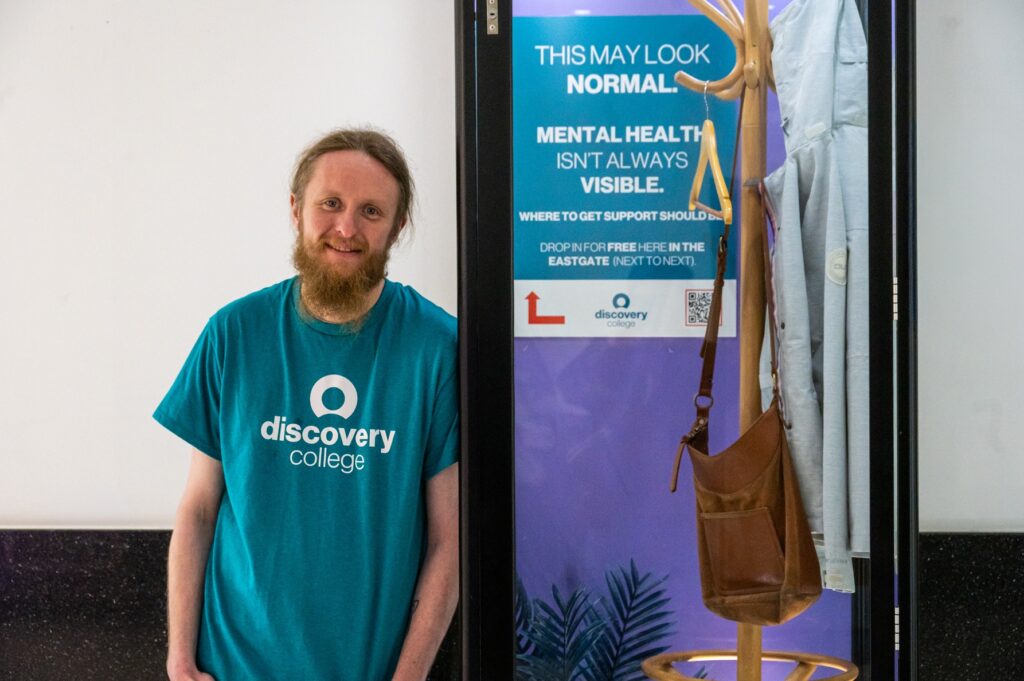 A man standing next to a display cabinet about mental health