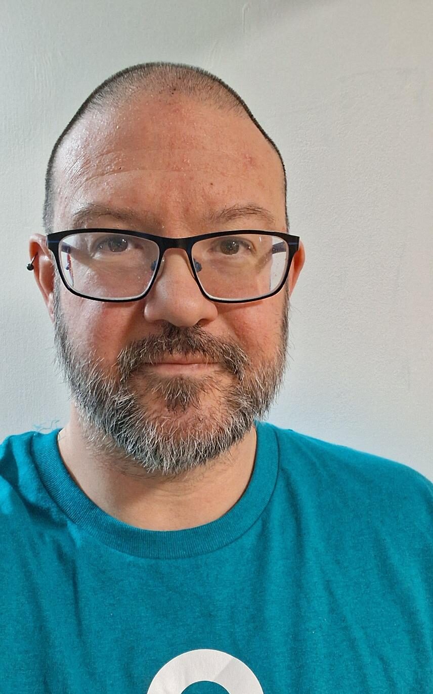 Man with glasses wearing a Discovery College t-shirt