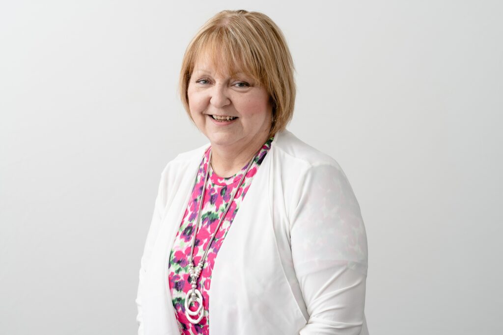 Photo of a woman smiling with blonde hair and a neutral background