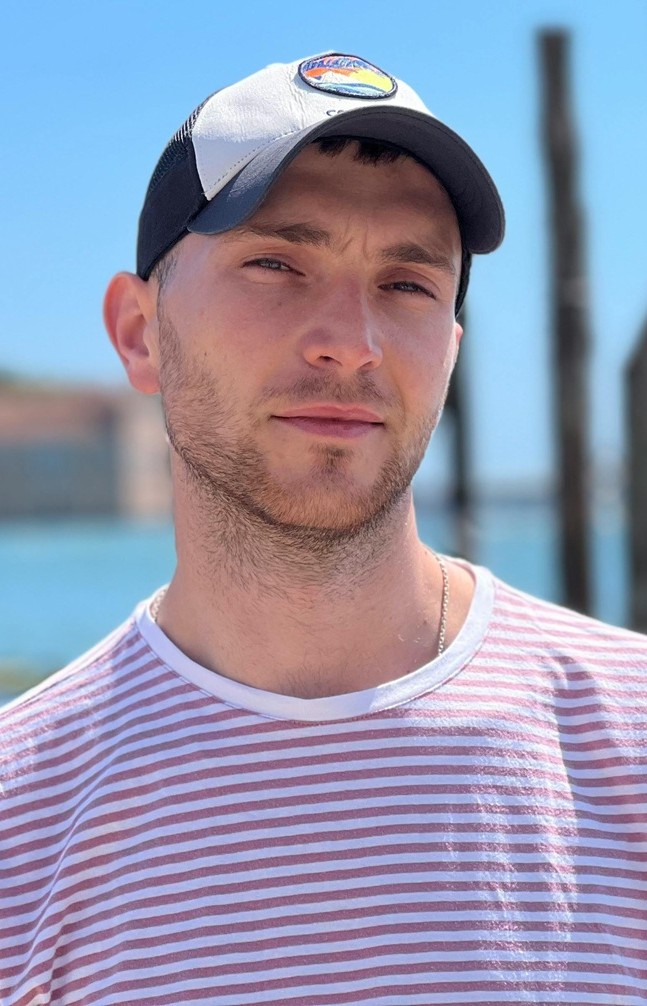Man wearing baseball cap and striped t-shirt with blue sky background
