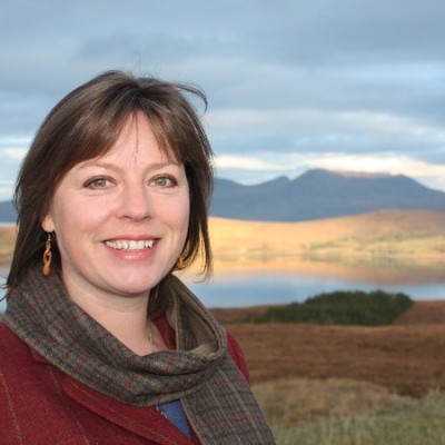 Woman with shoulder length brown hair smiling with mountain view