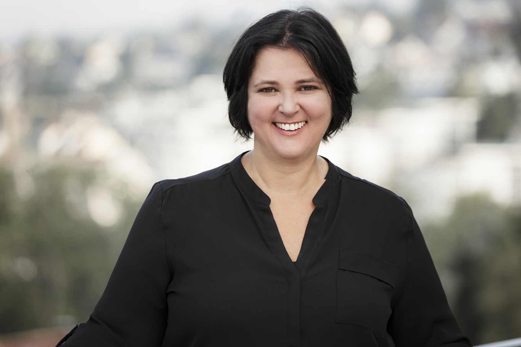 Woman with short dark hair and black shirt smiling at the camera