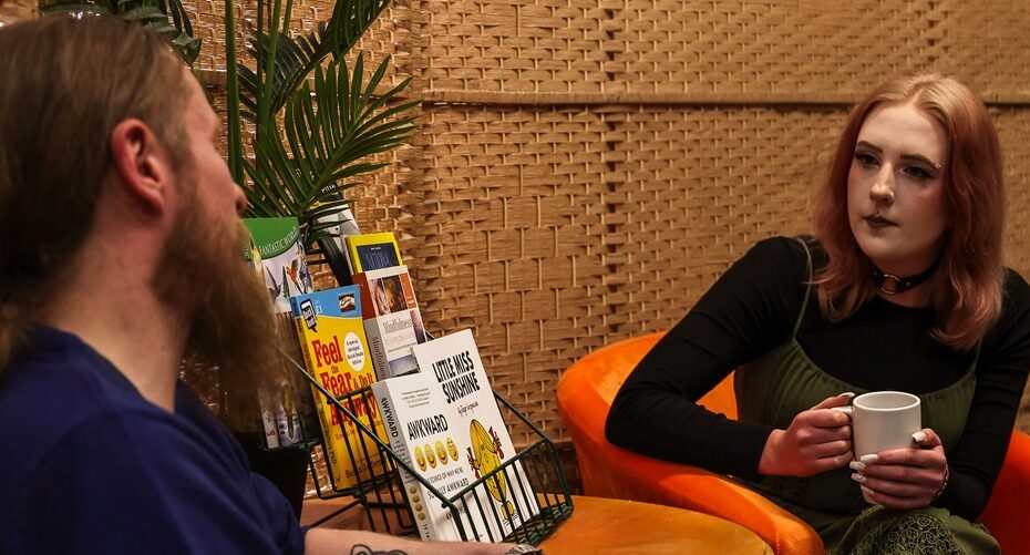 Two people sitting talking with a hot drink