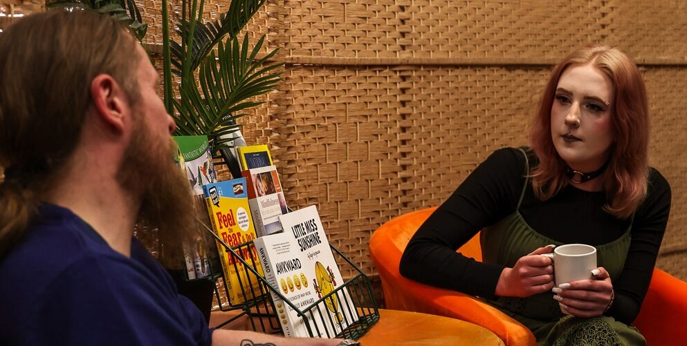 Two people sitting talking with a hot drink
