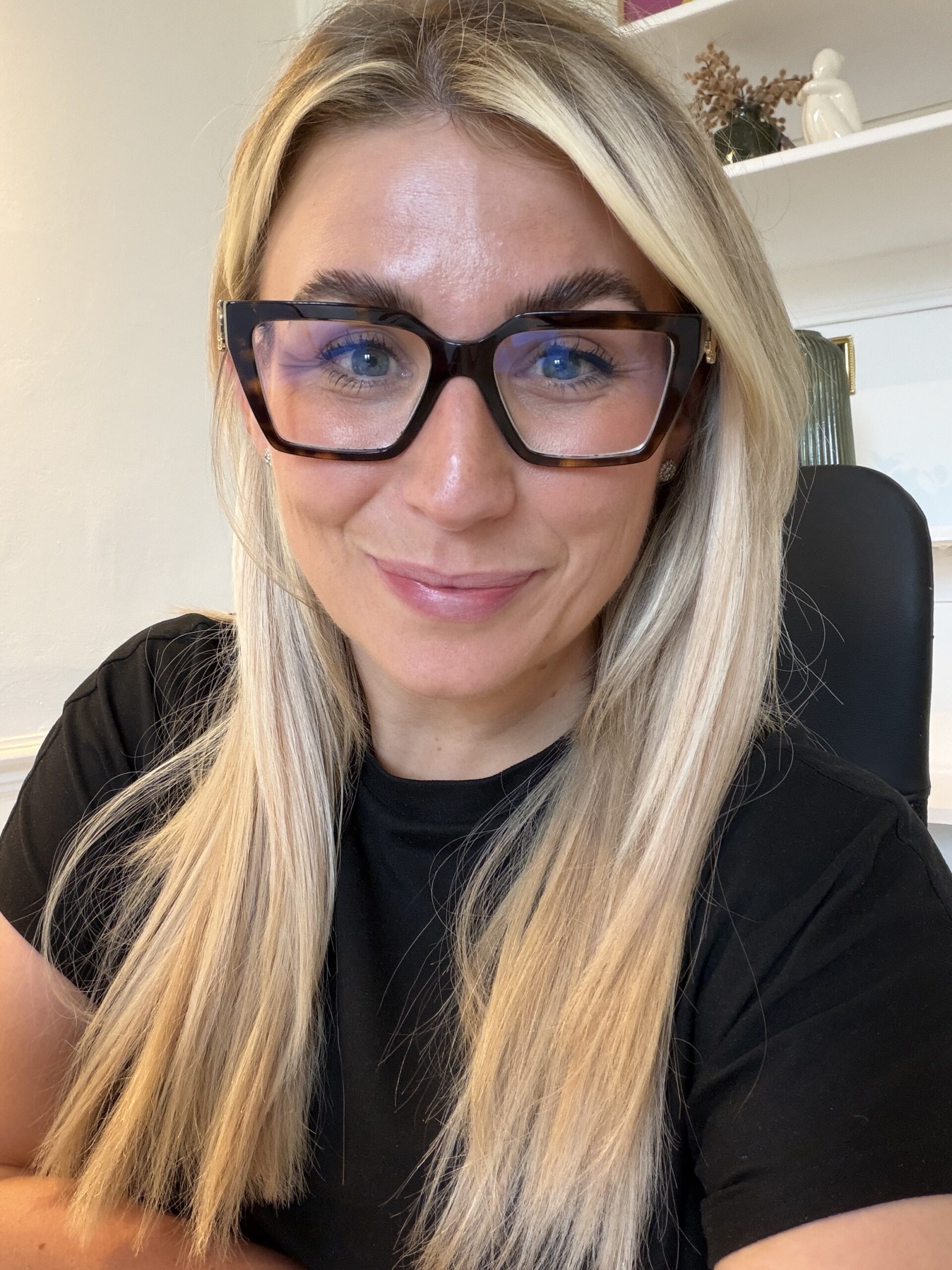Photo of a woman with long blonde hair and glasses smiling at the camera