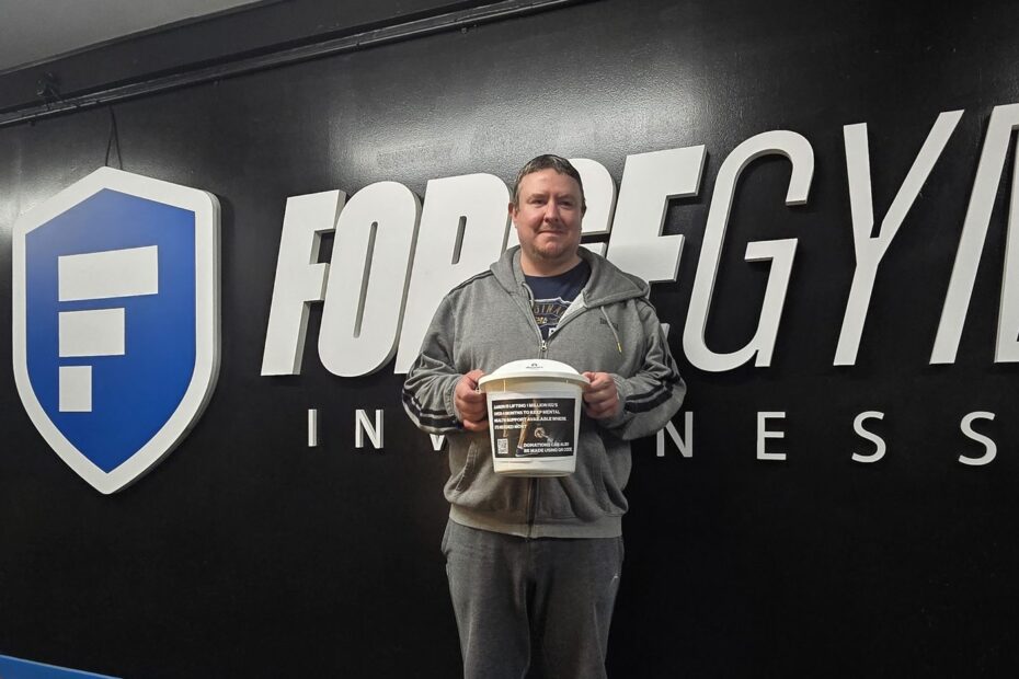 A man in gym clothes holding a donation bucket