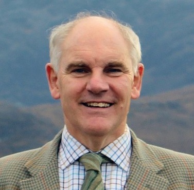 Photo of an older man with white hair wearing a suit