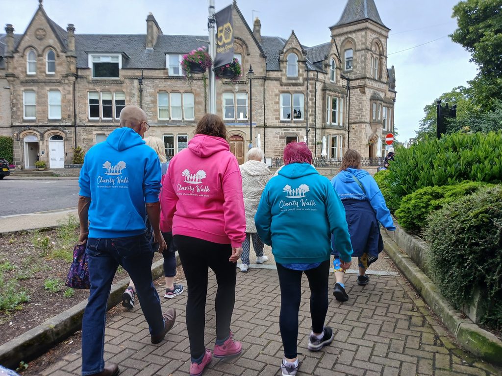 Photo of the backs of people walking with Clarity Walk hoodies on