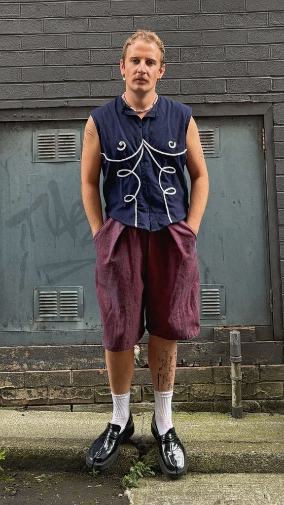 Photo of a fashion designer wearing a patterned waistcoat and shorts.